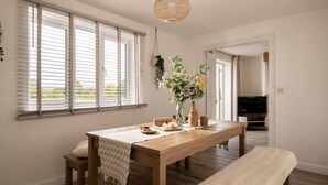 Un coin repas avec une table en bois, des bancs et une plante suspendue.
