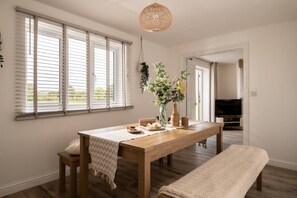 A dining area with a wooden table, benches, and a hanging plant.