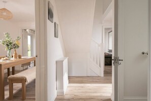 A hallway with a wooden floor, white walls, and a door leading to another room. - Hambledon Hill Cottage with Private Hot Tub (Blandford Forum)