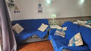 Una habitación con dos sofás azules, una mesita con una lámpara y un adorno en la pared.