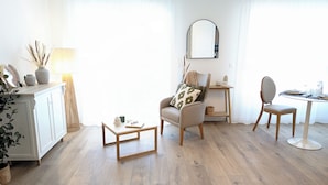 Un salon moderne avec un plancher en bois, un meuble blanc, une table de salle à manger ronde et un fauteuil confortable.