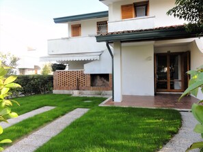 Una casa de dos pisos con un porche cubierto y un muro de ladrillo.