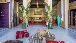 A traditional interior with a sofa set, decorative pillows, a chandelier, and a coffee table with traditional items. - Palais Andara Riad And SPA (Marrakech)