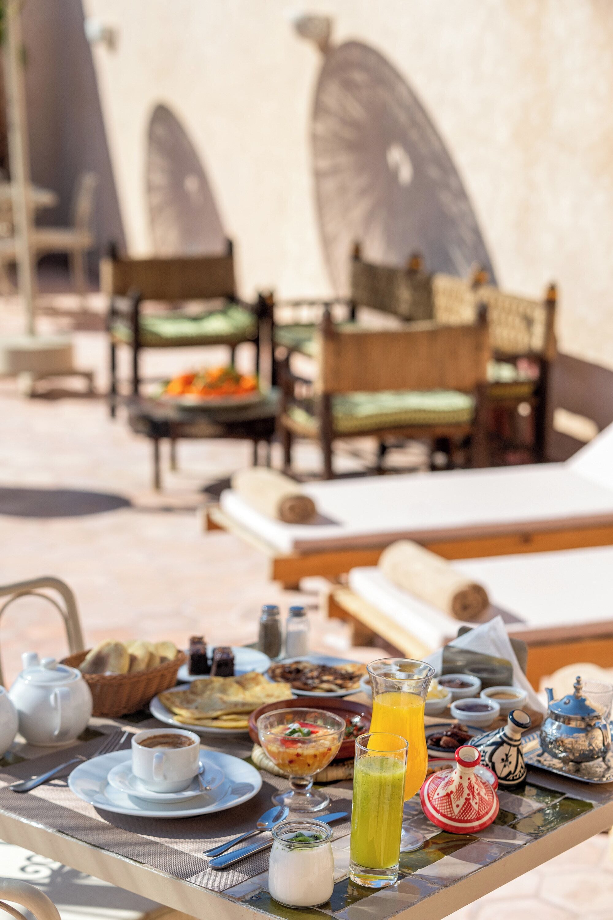 A breakfast table with various dishes, a pitcher of orange juice, and a teapot.