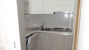 A compact kitchen with a built-in microwave, a sink, and a stove. - Charming Renovated Flat (San Michele al Tagliamento)