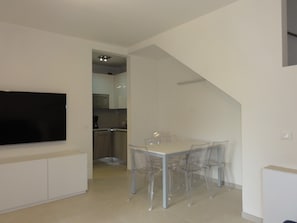 Eine moderne Küche mit weißen Schränken, einer eingebauten Mikrowelle und einem Edelstahl-Kühlschrank.