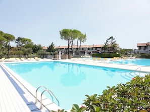 Una piscina con sillones de descanso y un bordeado de baldosas.