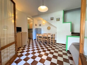 A compact kitchen with a checkered floor, a dining area with a table and chairs, and a kitchenette with a green accent wall. - Bright Two-storey Flat (San Michele al Tagliamento)