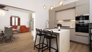 Une cuisine moderne dotée d’un îlot central, de tabourets de bar et d’un coin repas avec une table et des chaises.