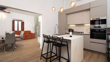 A modern kitchen with a central island, bar stools, and a dining area with a table and chairs.