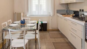 Eine moderne Küche mit weißen Schränken, einem Glastisch und weißen Stühlen.