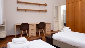 Ein Hotelzimmer mit Bett, Schreibtisch mit zwei Stühlen, Kleiderschrank und Heizkörper.