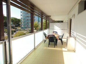 Un balcón con mesa y sillas, vista a edificios y suelo de baldosas.