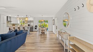 Une cuisine moderne avec des meubles blancs, un coin repas doté d’un canapé bleu et d’un banc en bois.