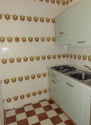 A kitchen with checkered flooring, light blue cabinets, and a gas stove. - Lovely Two-storey Flat (San Michele al Tagliamento)