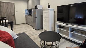 A compact living space with a kitchenette, a dining area, and a seating area with a TV. - Pool Side Retreat- 1 BED TC-B105 (Sa Khu)
