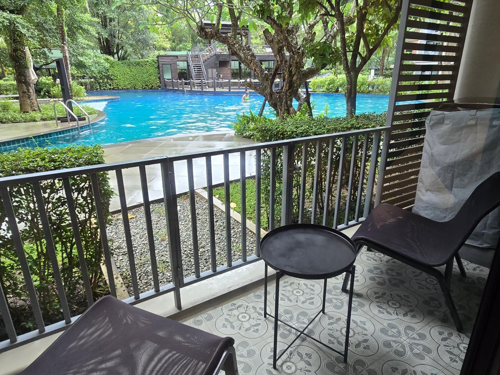 A balcony with a pool view, a chair, and a small table.