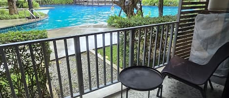 A balcony with a pool view, a chair, and a small table.