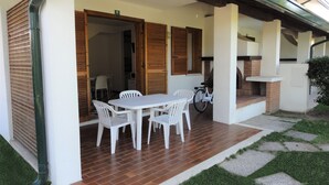 An outdoor patio with a table and chairs, a bicycle, and a brick fireplace. - Charming Two-storey Flat (San Michele al Tagliamento)