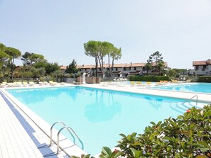 A swimming pool with lounge chairs and a tiled deck. - Charming Two-storey Flat (San Michele al Tagliamento)