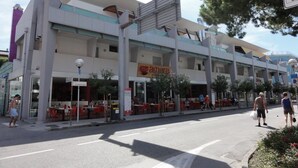 A multi-story building with outdoor seating and a restaurant sign. - Bright Apartment Near the Beach (San Michele al Tagliamento)