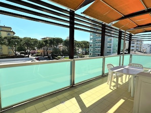 Ein Balkon mit Blick auf eine Wohngegend, mit Bäumen und Häusern.