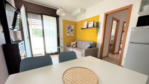 A dining area with a white table, blue chairs, and a woven placemat. - Bright Apartment Near the Beach (San Michele al Tagliamento)