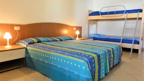 Una habitación con una cama individual, una litera, dos mesitas de noche con lámparas y un cabecero de madera.