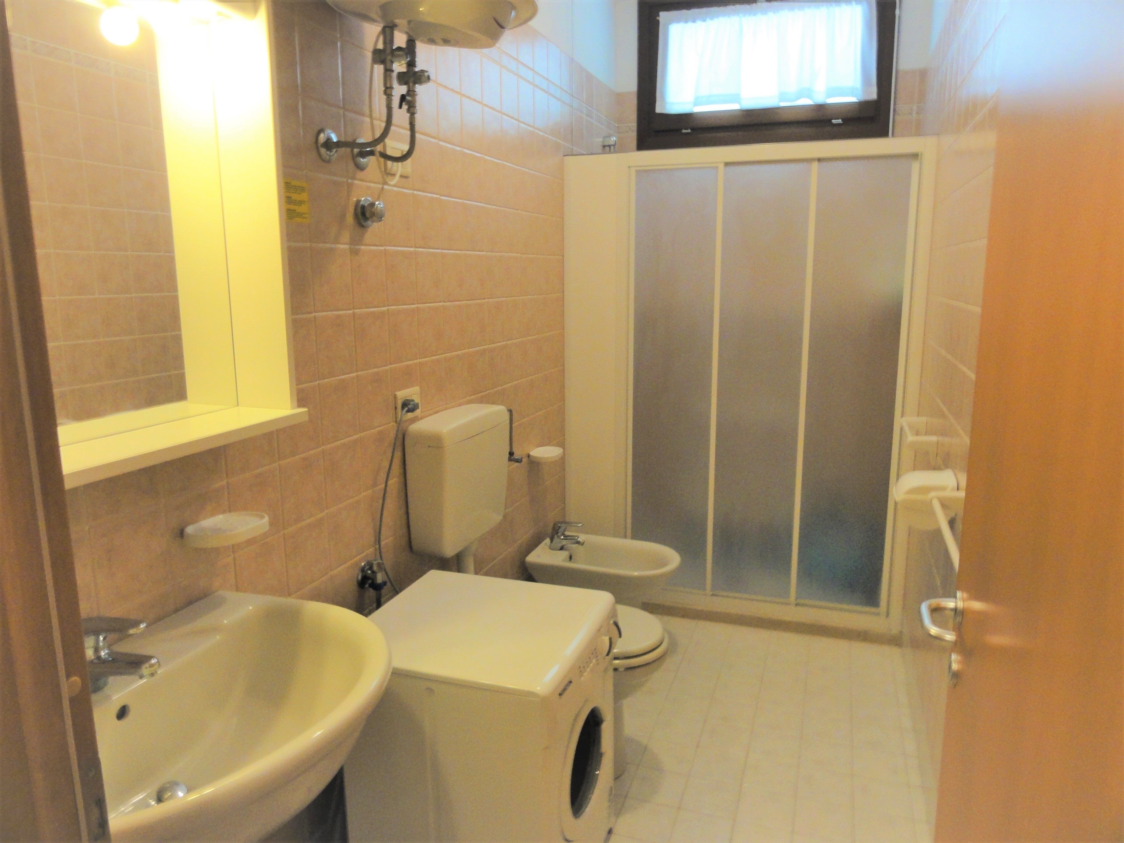 Un baño pequeño con lavamanos, inodoro y lavadora.