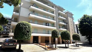A multi-story residential building with balconies, a parking area, and a bicycle storage area. - Cozy Apartment Close to the Beach (San Michele al Tagliamento)