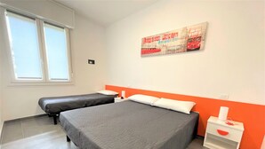Hotellihuone, jossa on kaksi sänkyä, ikkuna ja juliste seinällä.
