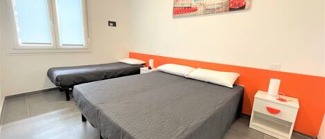 A hotel room with two beds, a window, and a poster on the wall.