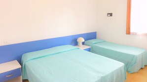 A room with two single beds, a nightstand, and a window with a curtain. - Cozy Flat in a Villa With Garden (San Michele al Tagliamento)