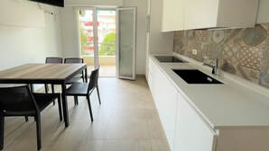 A modern kitchen with white cabinets, a black countertop, and a tiled backsplash. - Modern Apartment in Central Location (San Michele al Tagliamento)