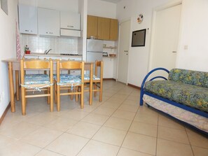 Espaço compacto com área de refeições, cozinha compacta e sofá.