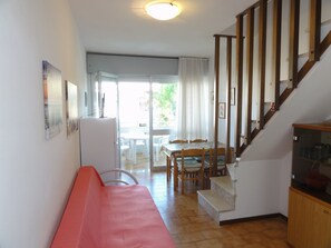 A compact living space with a kitchenette, a dining area, and a staircase. - Flat With Terrace Close to Beach (San Michele al Tagliamento)