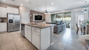 Una cocina moderna con armarios blancos, un refrigerador de acero inoxidable y una isla integrada con un lavamanos.