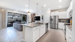 A modern kitchen with white cabinetry, stainless steel appliances, and a central island. - Luxury 5BR Villa w/ Pool & Themed Rooms (DAVENPORT)