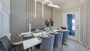 A modern dining area with a checkered tablecloth, grey chairs, and a contemporary light fixture. - Luxury 5BR Villa w/ Pool & Themed Rooms (DAVENPORT)