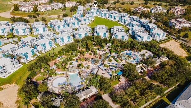 An aerial view of a resort with multiple buildings, a central pool, and surrounding greenery. - Modern 2-Story Loft w/ Pool Table – Near Disney (Kissimmee)