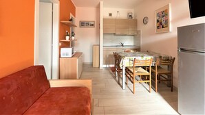 A compact kitchen with a dining area, a sofa, and a refrigerator. - First Floor Flat With Terrace and Pool Access (San Michele al Tagliamento)