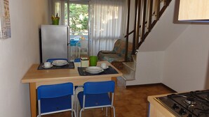 Eine kompakte Küche mit Esstisch, Stühlen, Kühlschrank und Herd.