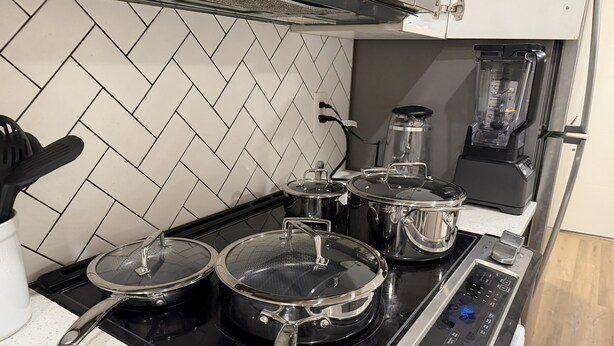 A kitchen with a black stove, stainless steel pots, a coffee maker, and a blender. - Cozy Basement Suite in Mahogany (Calgary)
