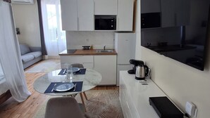 A compact kitchen with white cabinets, a microwave, and a large flat-screen TV mounted on the wall. - Le Bali Zen, studio with jacuzzi (Charavines)