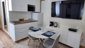 A compact kitchen with white cabinets, a microwave, and a large flat-screen TV mounted on the wall. - Le Bali Zen, studio with jacuzzi (Charavines)