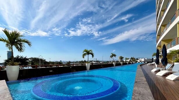 A swimming pool with a circular design, surrounded by a wooden deck and palm trees. - 4BR Marina Ocean-View Above Casino 2 Suites (Puerto Vallarta)