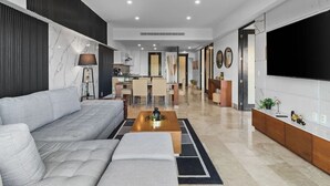A modern living room with a grey sofa, a coffee table, and a TV mounted on the wall. - 4BR Marina Ocean-View Above Casino 2 Suites (Puerto Vallarta)