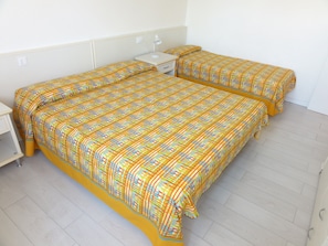 A double bed with a patterned bedspread, a bedside table, and a nightstand. - Terraced Villa With Garden and Pools (San Michele al Tagliamento)