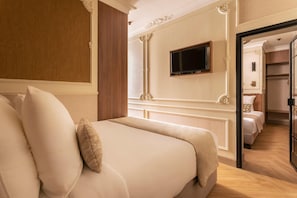 A hotel room with a large bed, a television mounted on the wall, and a view into the adjacent room. - Luxury Suite - Wagram (Paris)