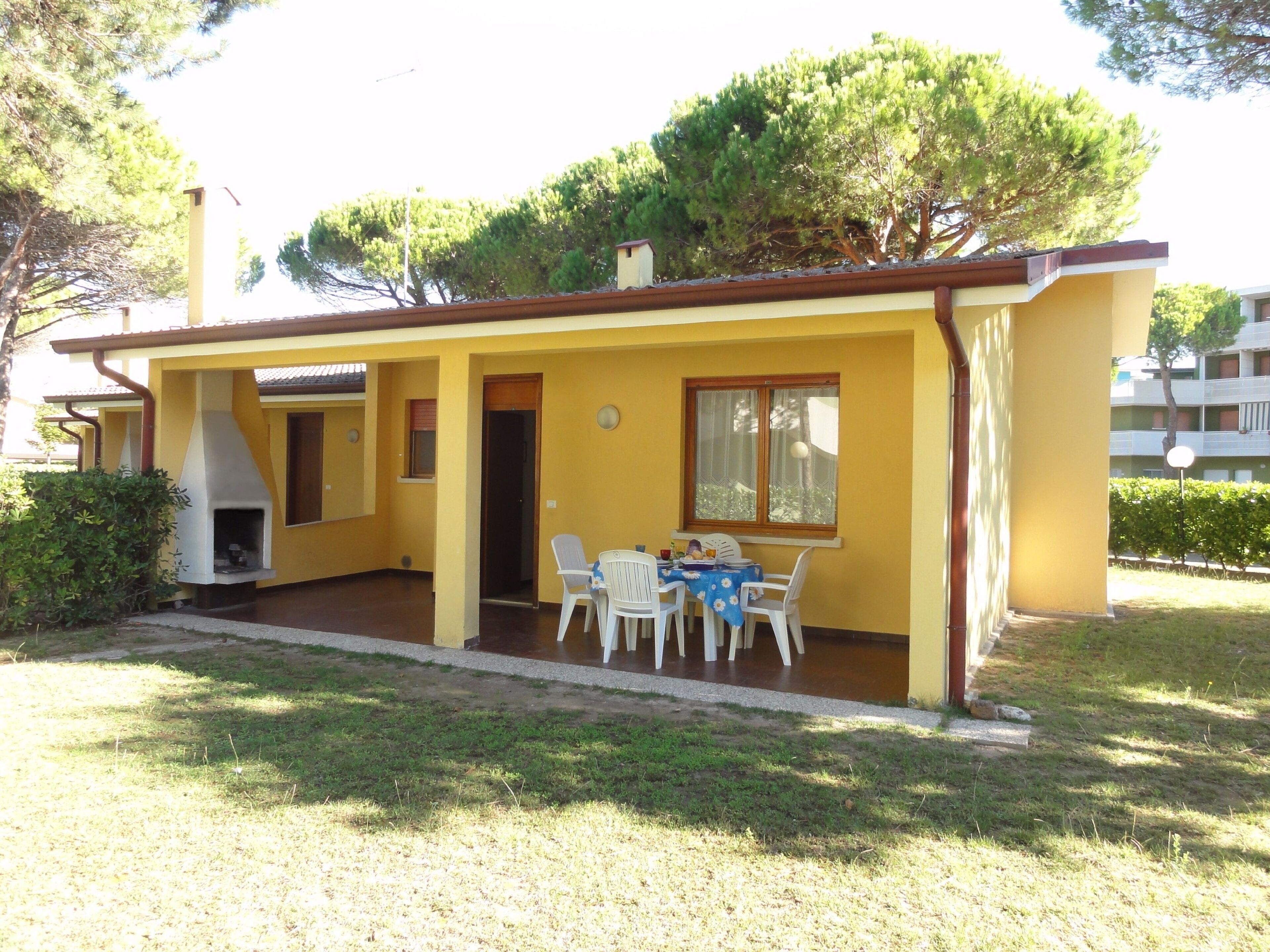 Un edificio amarillo con un patio, una parrilla y una mesa con sillas.
